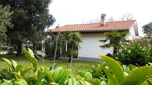 Un edificio con tetto in tegole rosse, circondato da rigogliosa vegetazione e alberi.