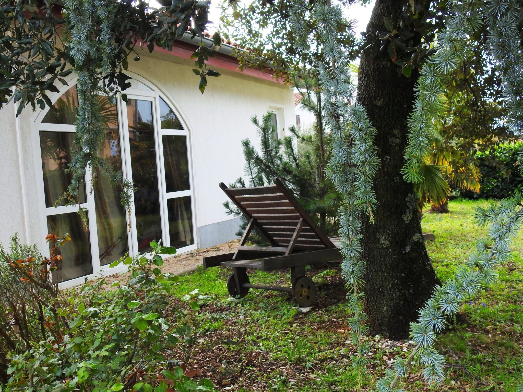 A wooden bench in a garden with a white building in the background.