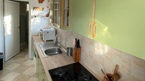 Una cucina con mobili verdi, un piano cottura nero, un lavandino e un bollitore bianco.