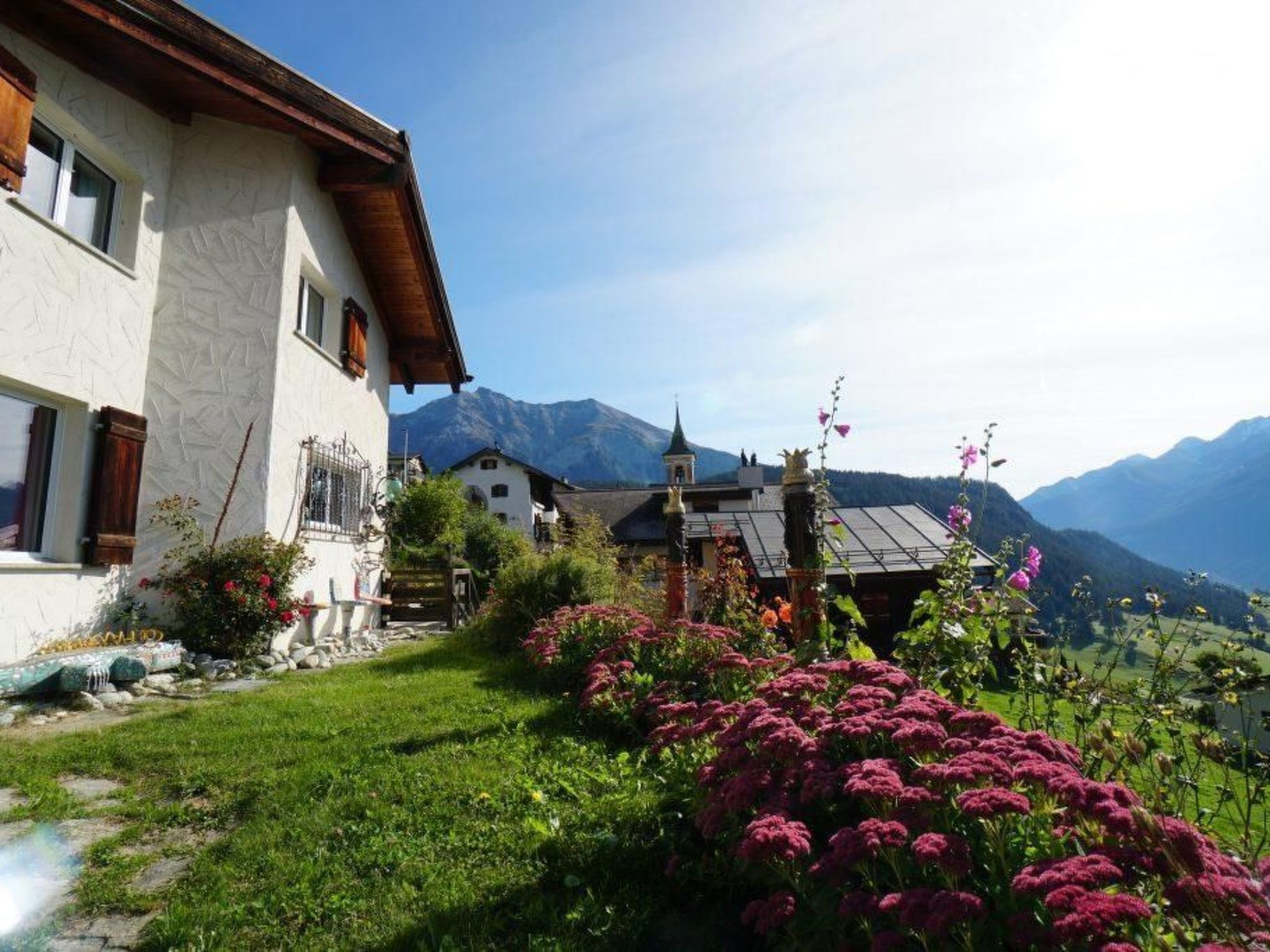 Ein traditionelles Chalet mit Natursteinfassade, Holzdach und einem Garten voller bunter Blumen.