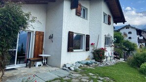 A white building with wooden shutters, a stone patio, and a bench. - Sin Sponda by Interhome (Vaz)