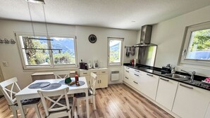 A modern kitchen with white cabinets, a black countertop, and a view of mountains through the windows.