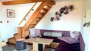 A cozy living room with a wooden staircase, a purple sofa, and a small table with a plant. - Haus Laura, Radslav by Interhome (Cerna v Posumavi)