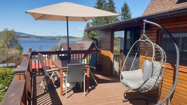 A wooden deck with a table and chairs, a hanging chair, and a large umbrella. - Haus Laura, Radslav by Interhome (Cerna v Posumavi)