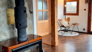A cozy room with a fireplace, wooden door, and a chair by a window. - Haus Laura, Radslav by Interhome (Cerna v Posumavi)