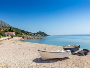A beach with a row of boats and a building with a red roof. - Maric mit Terrasse und Balkon by Interhome (Podstrana)
