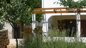 Ein weißes Gebäude mit einer Holzpergola und einer Steinmauer.