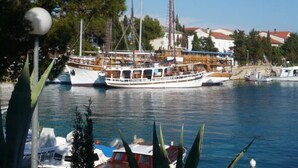 Ein Yachthafen mit mehreren vor Anker liegenden Booten, darunter eine große Segelyacht mit mehreren Masten.