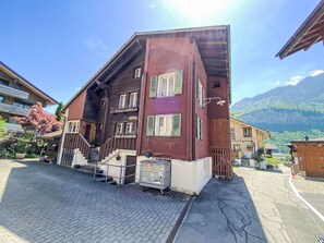A traditional chalet with a sloped roof, wooden balconies, and a paved entrance area. - Wenger 5-Bettwohnung by Interhome (Meiringen)