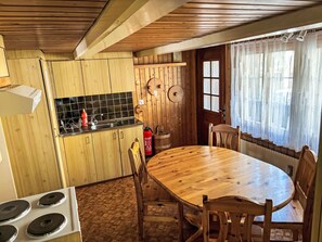 A wooden kitchen with a stove, sink, and dining table with chairs. - Wenger 5-Bettwohnung by Interhome (Meiringen)