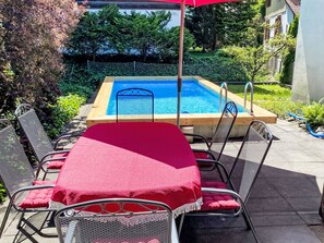 A poolside area with a pool, chairs, and a table covered with a red cloth. - Wenger 5-Bettwohnung by Interhome (Meiringen)