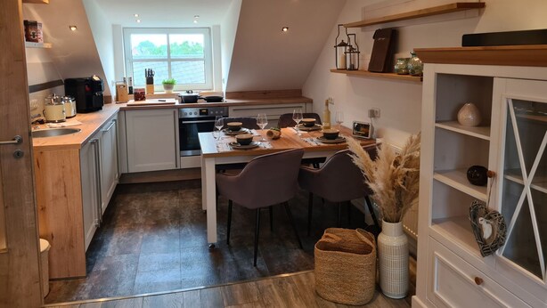 Una cocina moderna con comedor, que incluye horno empotrado, cafetera y ventana con vistas a la vegetación.