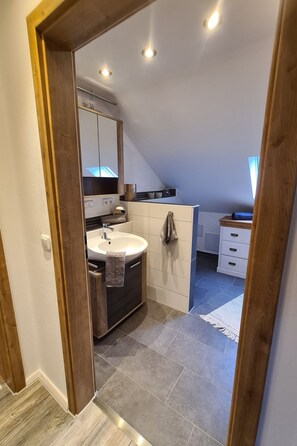 Een moderne badkamer met een vrijstaand bad, een grote spiegel en een wastafelmeubel met een wastafel.