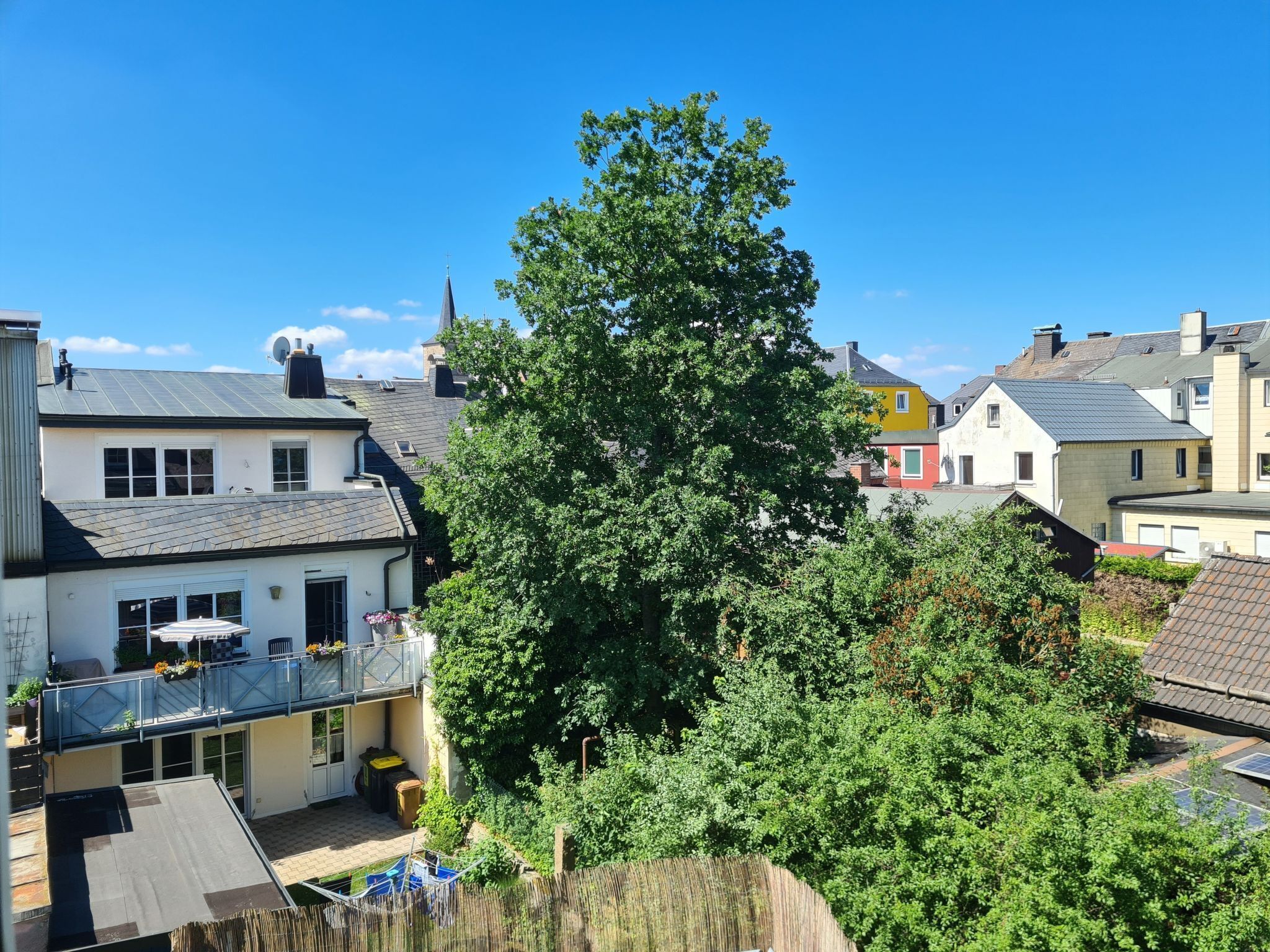 Ein Wohngebiet mit Häusern, einem großen Baum und blauem Himmel.