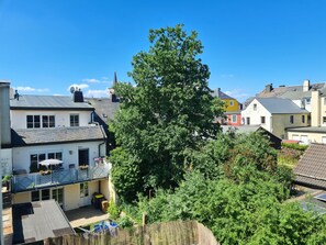 Een woonwijk met huizen, een grote boom en een helderblauwe lucht.