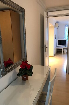 Ein Flur mit einem weißen Konsolentisch, einem Spiegel und einer Topfpflanze.