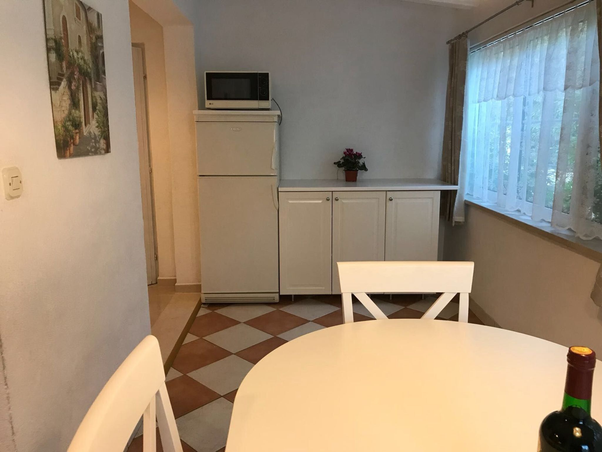 A small kitchen with a microwave, a refrigerator, and a dining table with chairs.