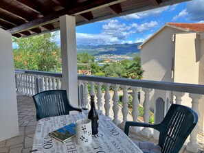 A balcony with a table set for two, featuring a book, a bottle, and a decorative mug. - Apartment Horvat by Interhome (Polje)