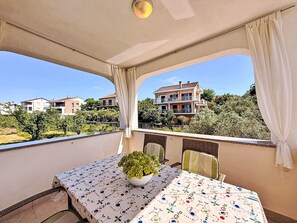 Ein Balkon mit Tisch, Stühlen und einem Blumentopf.