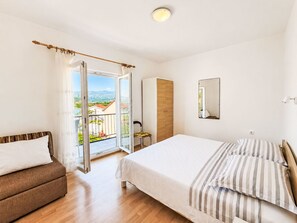 Ein Schlafzimmer mit Bett, Stuhl, Kleiderschrank, Spiegel und einem Balkon mit Blick.