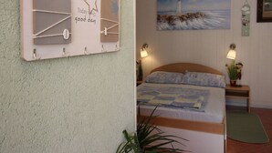 A room with a bed, a wall-mounted bulletin board, a painting of a lighthouse, and a small plant. - Apartment Renata by Interhome (Polje)