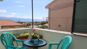 A balcony with two turquoise chairs, a small round table, and potted plants. - Apartment Renata by Interhome (Polje)