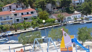 Ein Spielplatz mit Rutsche und Schaukeln in der Nähe eines Yachthafens mit Booten.