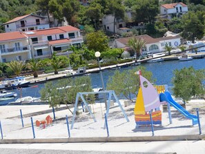 A playground with a slide and swings near a marina with boats. - Schöne Wohnung in Poljica mit privatem Parkplatz by Interhome (Marina)