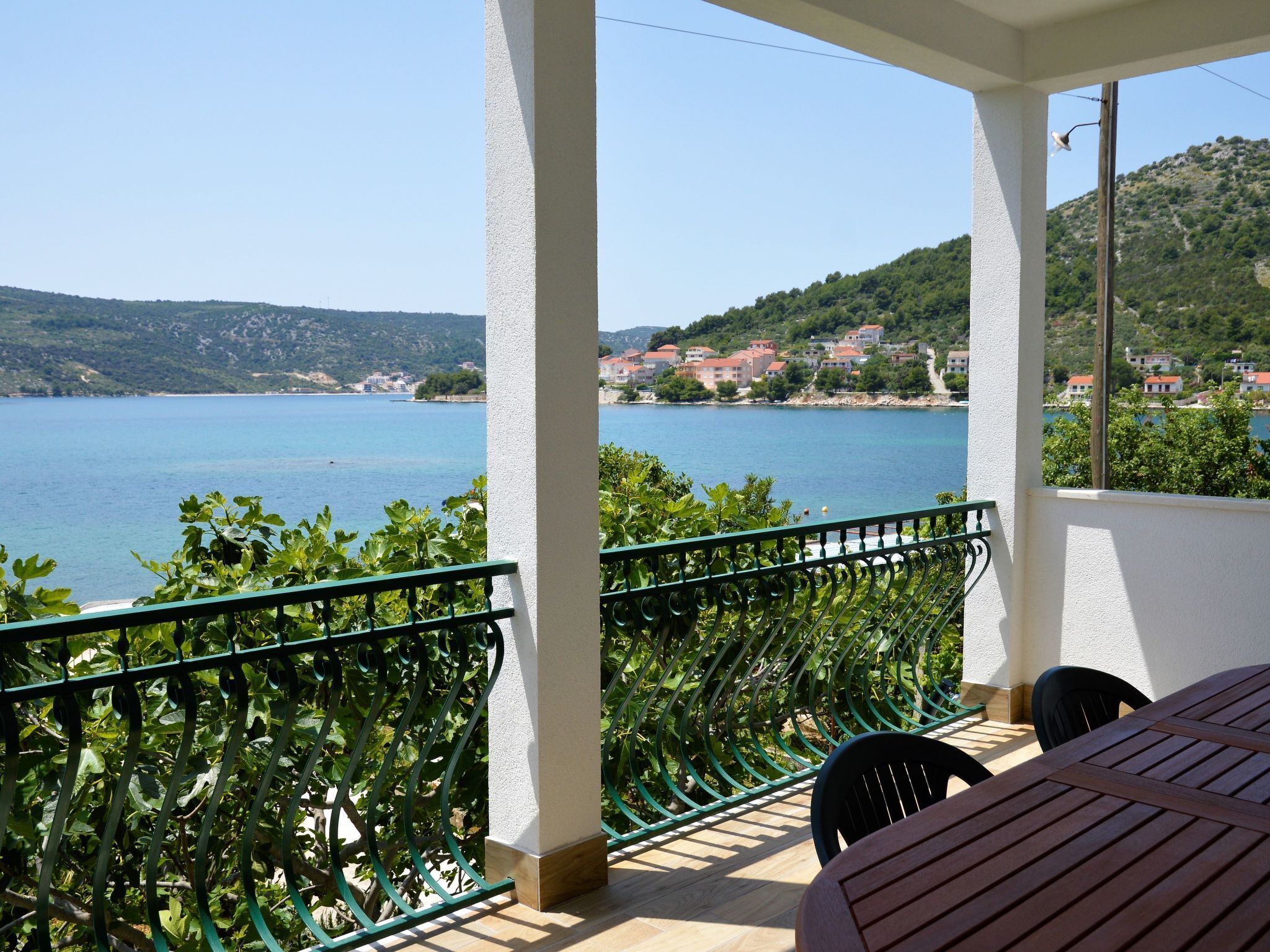 A balcony with a view of a lake and hillside houses.