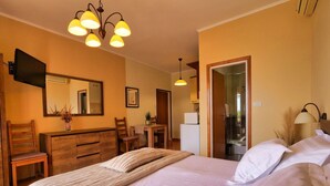 Una camera da letto con un letto grande, una scrivania, una sedia, uno specchio e un angolo doccia.