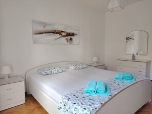 Ein Schlafzimmer mit Bett, Nachttisch, Kommode, Spiegel und einem Bild an der Wand.