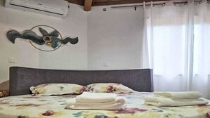 Una cama con colcha estampada, cabecera y un adorno en la pared.