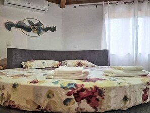 A bed with a floral bedspread, a headboard, and a wall-mounted decorative item. - Das Haus der Weinkellerei by Interhome (Cabo da Praia)