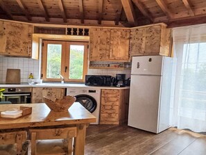 A rustic kitchen with wooden cabinets, a built-in oven, a washing machine, and a refrigerator. - Das Haus der Weinkellerei by Interhome (Cabo da Praia)