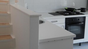 Moderni keittiö, jossa on valkoiset kaapit, ruostumattomasta teräksestä valmistettu liesituuletin ja sisäänrakennettu uuni.