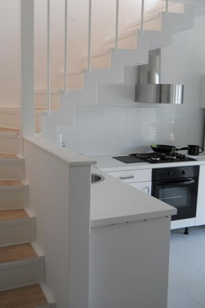 Eine moderne Küche mit weißen Schränken, einer Edelstahl-Dunstabzugshaube und einem eingebauten Backofen.