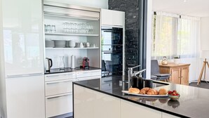 Una cocina moderna con armarios blancos, encimera negra y vistas al exterior.