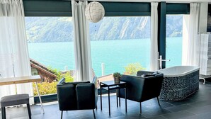 Una habitación moderna con vista a un lago, una bañera y un comedor.
