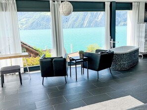 Ein modernes Zimmer mit Seeblick, einer Badewanne und einem Essbereich.