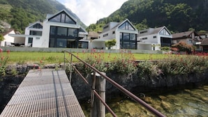 Et moderne boligområde med moderne huse, en træbro og et bjergrigt baggrundslandskab.