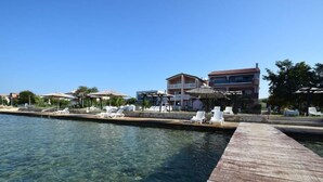 A waterfront hotel with clear water, wooden dock, and white lounge chairs. - Wohnung in Turanj mit Grill by Interhome (Donje Rastane)