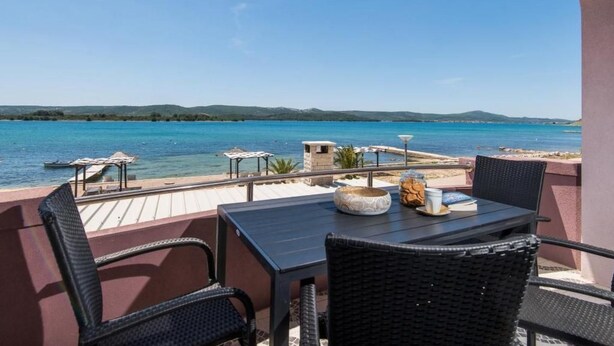 A terrace with a table and chairs overlooking a body of water. - Wohnung in Turanj mit Grill by Interhome (Donje Rastane)