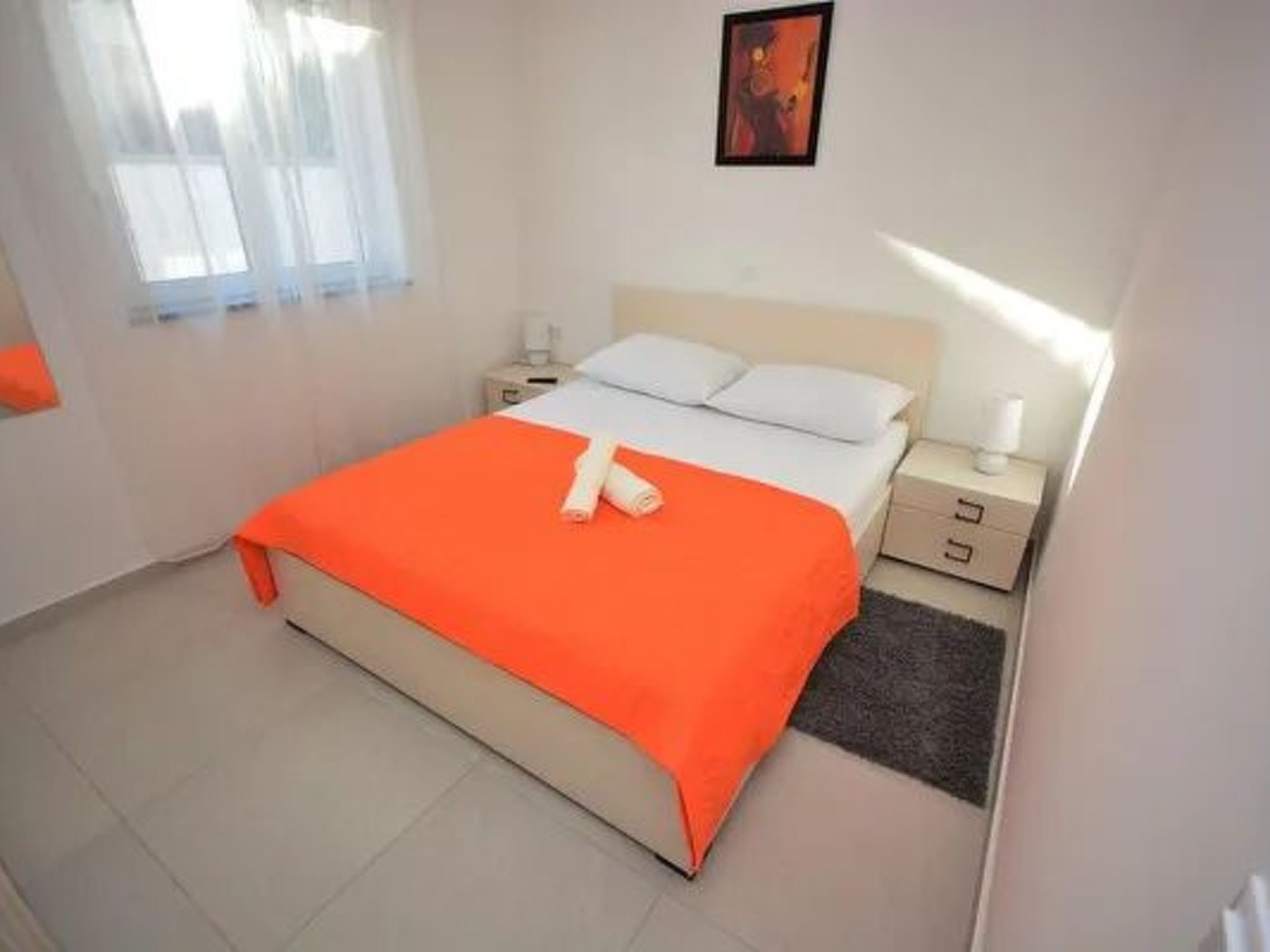 Ein Hotelzimmer mit einem Bett, einem Nachttisch, einer Lampe und einem gerahmten Bild an der Wand.