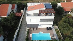 Una casa moderna de dos pisos con terraza en la azotea y piscina.