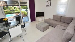 Una sala moderna con una mesa de comedor de vidrio, un sofá y un televisor.