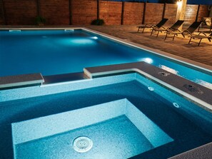 En swimmingpool med træterrasse og liggestole.