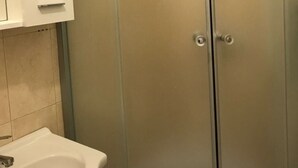 A bathroom with a white sink, a cabinet, and a frosted glass shower enclosure. - Ferienwohnung by Interhome (Orebić)