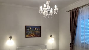 A bedroom with a bed, two bedside tables, a chandelier, a painting, and a window with curtains. - Ferienwohnung by Interhome (Orebić)