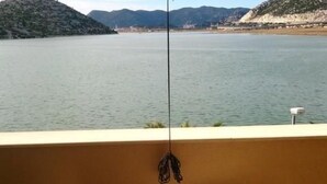 Un balcon donnant sur un lac paisible, avec une chaise et une table.