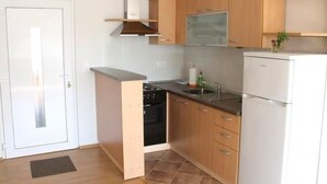 Une cuisine compacte avec des meubles de rangement en bois, un four encastré, un évier et un réfrigérateur.